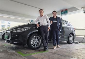 From L to R: Goh Chee Kiong, CEO of Charge+, and Adrian Lee, co-founder of Tribecar, in front of Tribecar vehicles at a Charge+ EV charging station